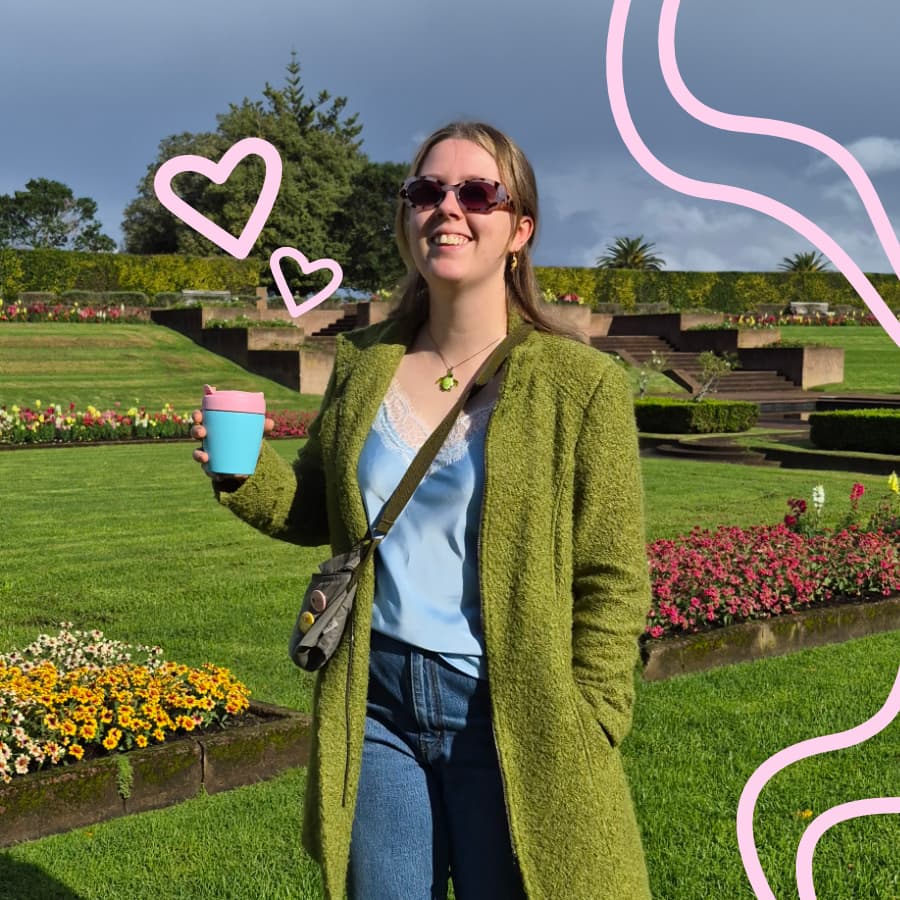 woman in green coat holding a coffee cup